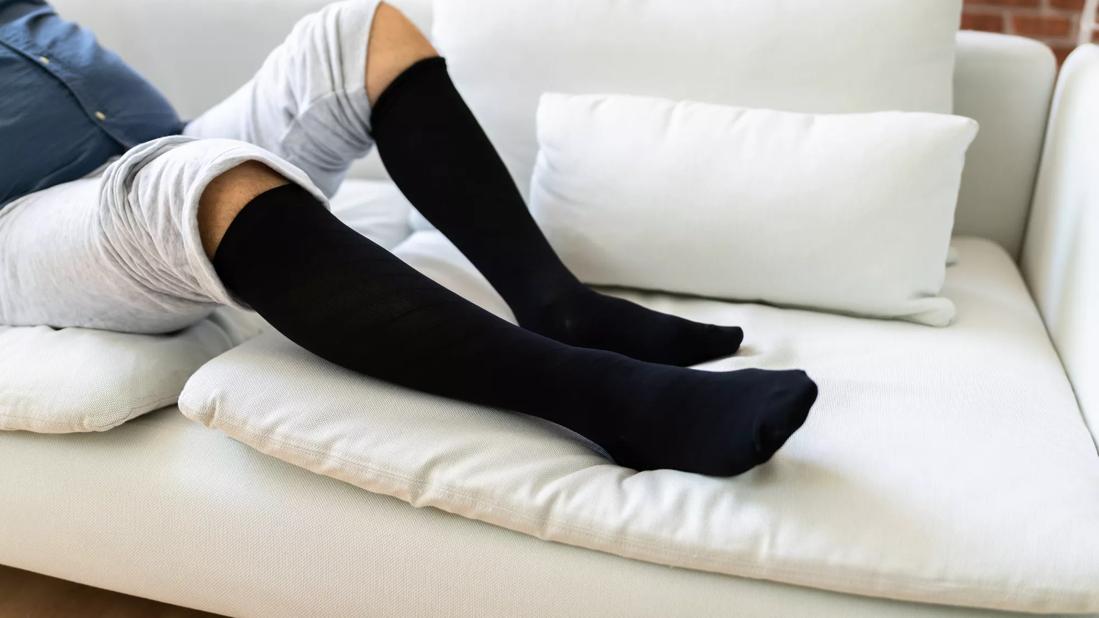 Person reclining on couch wearing compression socks