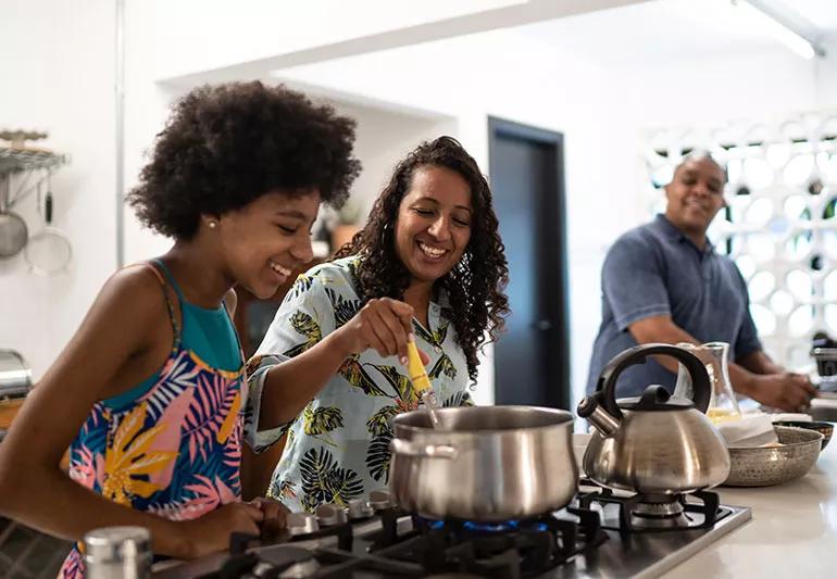 Two adults cooking dinner with a child