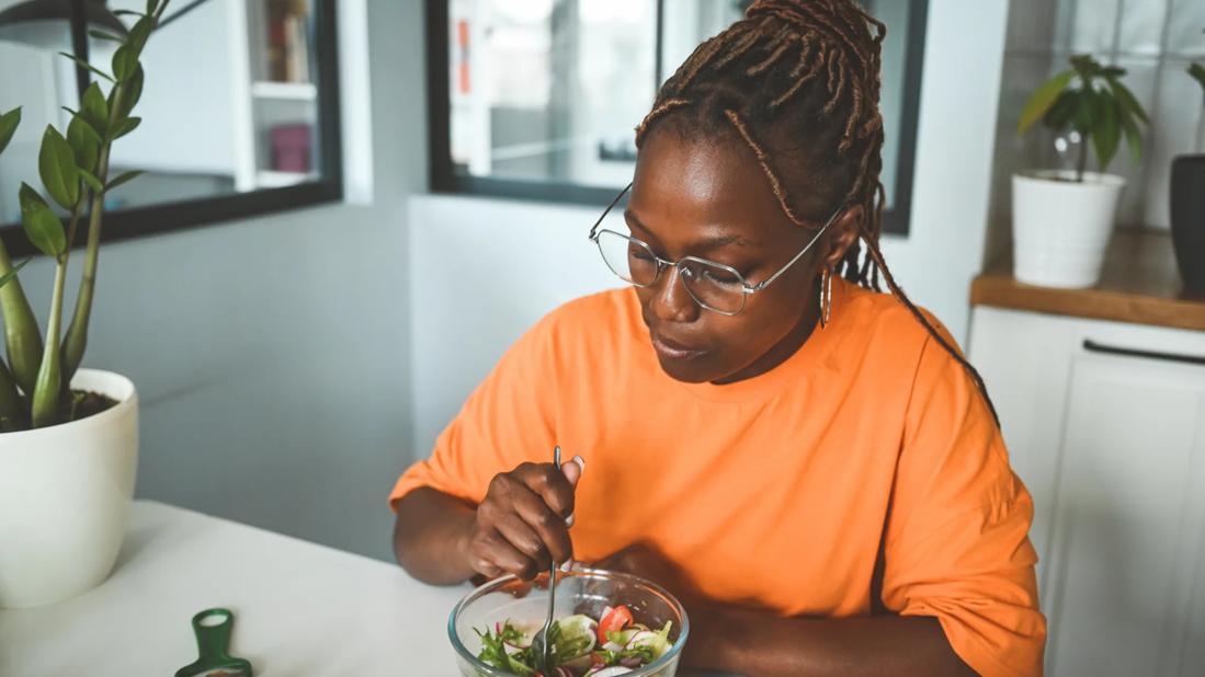 Woman eating a salad at her kitchen counter