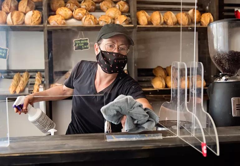 employee at bakery wearing a mask and working