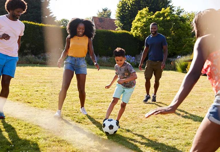 Family playing soccer in back yard