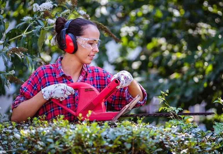 woman trimming header with eye and ear protection