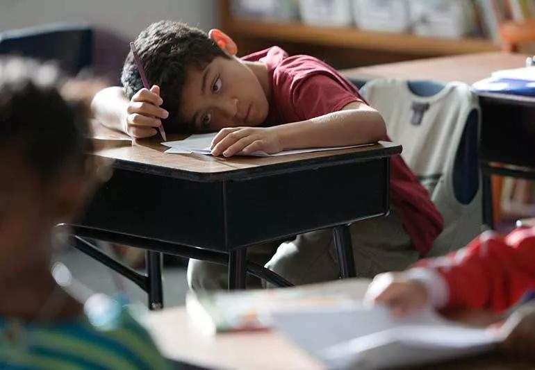 kid in class with head down on desk