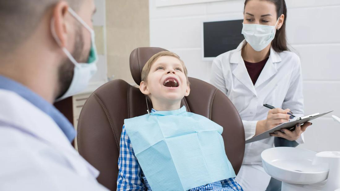 A child sitting in a dentist's chair with his mouth open