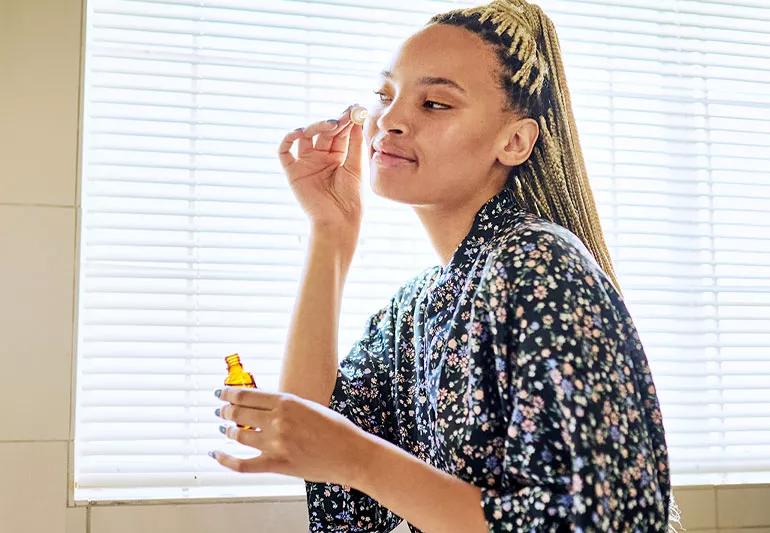 A person applies face oil to cheek.