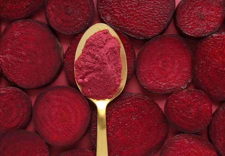 spoon full of beetroot powder over sliced beets
