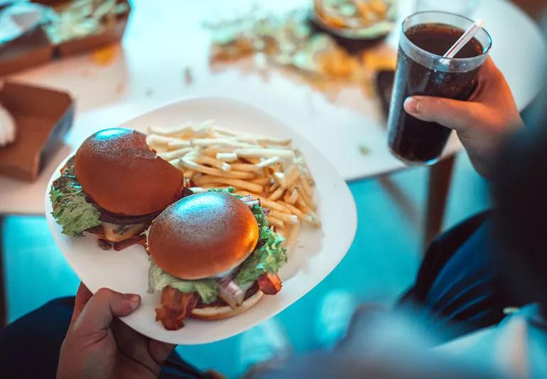 man eating hamburgers and fries at night