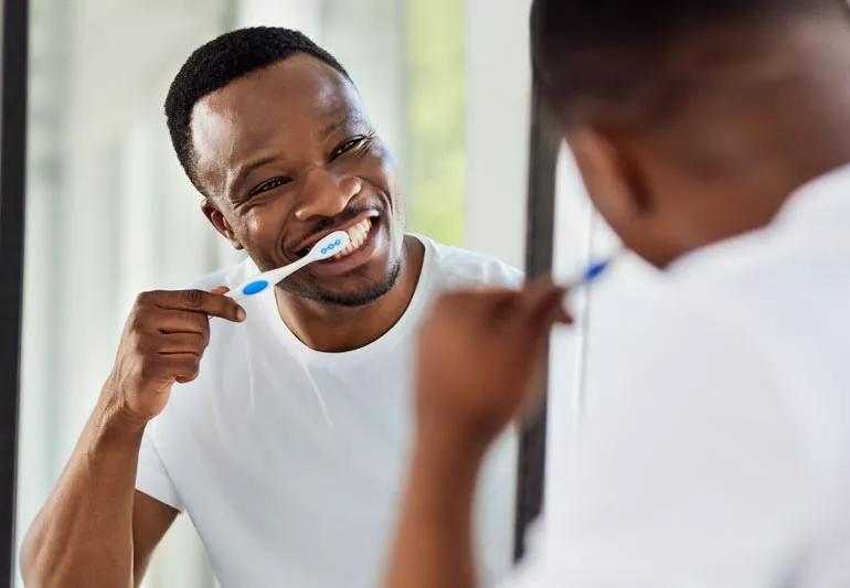 Person brushing teeth while looking in mirror in bathroom.
