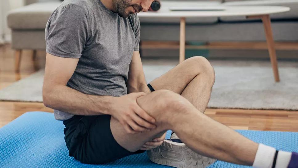 Person messaging thigh muscle on exercise mat