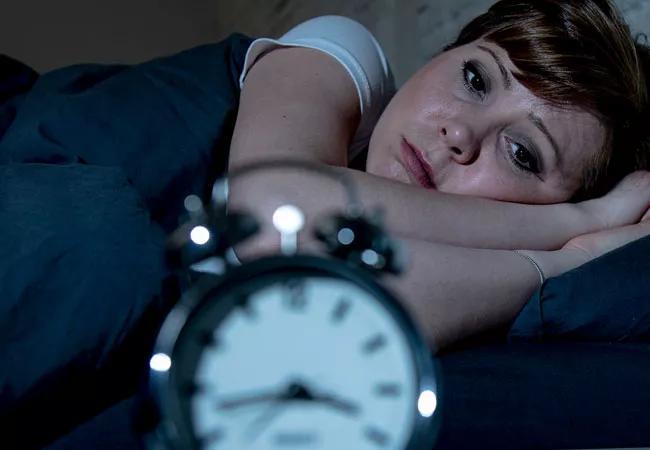 woman staring at alarm clock