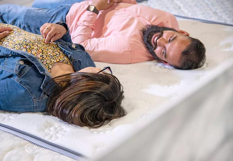 A couple lie on a matress at the store to test firmness.