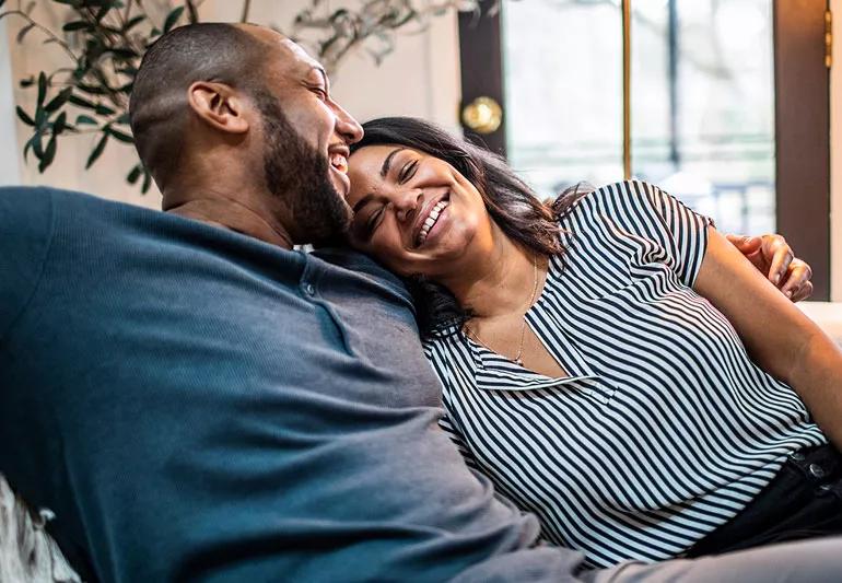 Loving couple embracing and laughing while relaxing on a couch.