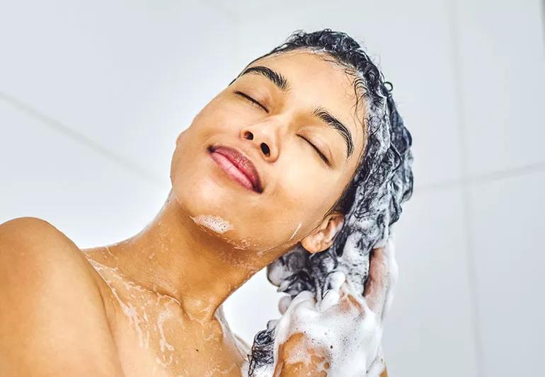 Woman washing her hair biiotin benefits hair loss