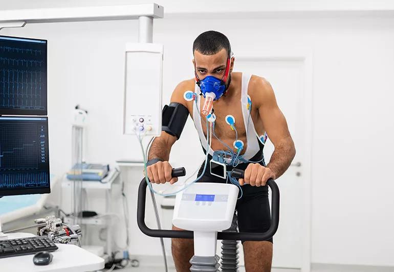 Person exercising on a machine while being monitored for breathing and heart rate