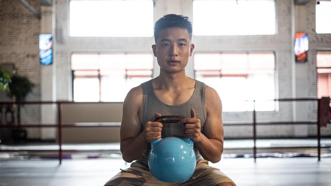 Person at gym doing goblet squat exercises with a kettle bell weight