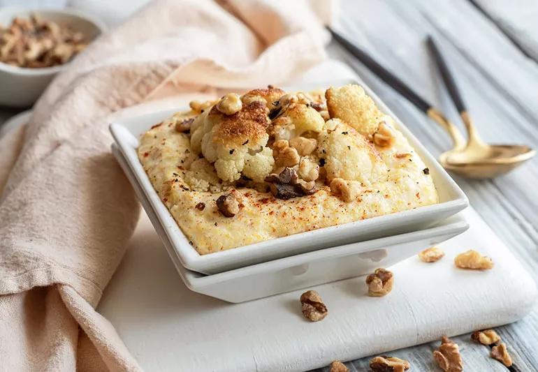 A bowl of polenta topped with roasted cauliflower and walnuts