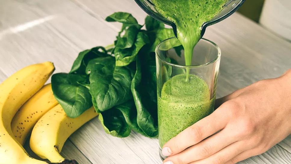 Pouring a homemade spinach and banana smoothie into a glass