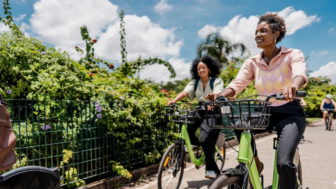 Smiling people riding bicycles on sunny day, blue sky