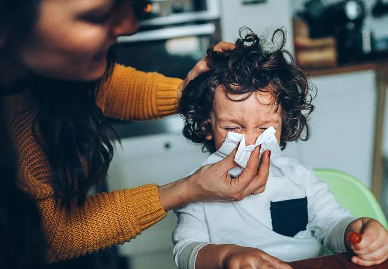 Mother wiping childs nose during cold season