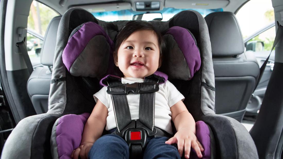 Older child belted into rear-facing care seat, in back seat of the car