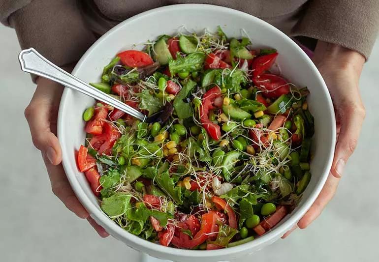 Person holding a salad in a bowl.