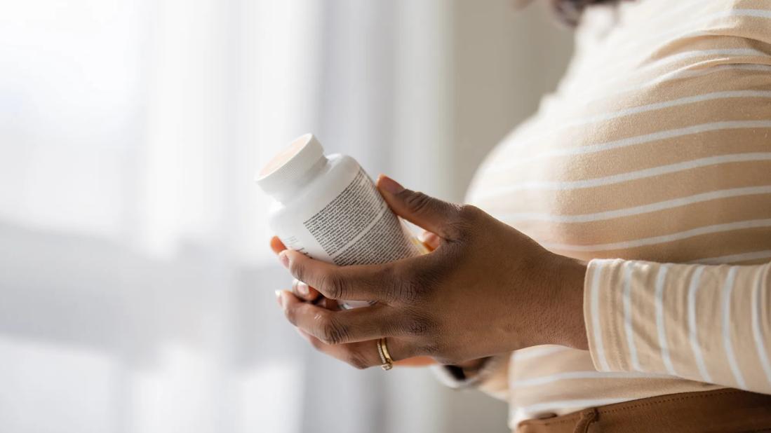 Person holding bottle of vitamins, reading the label