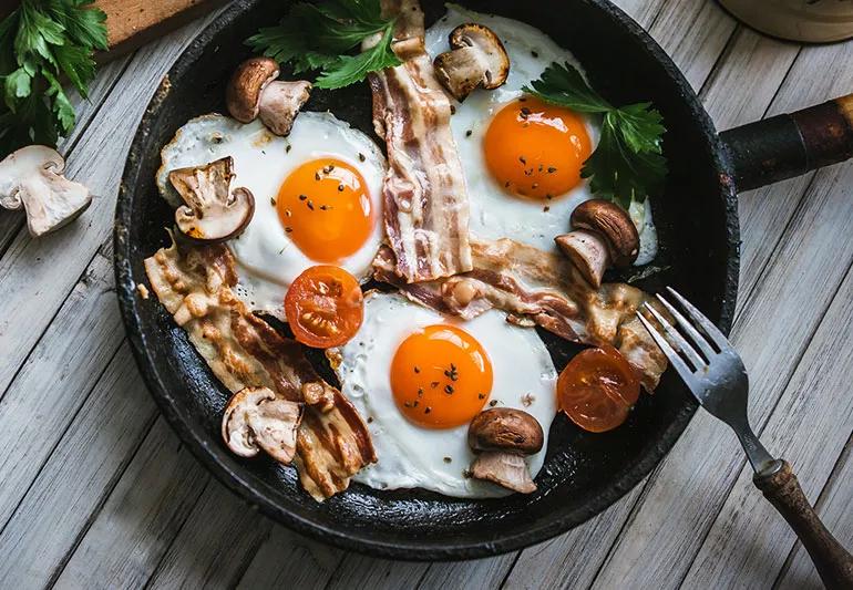 Frying up eggs and bacon in a skillet