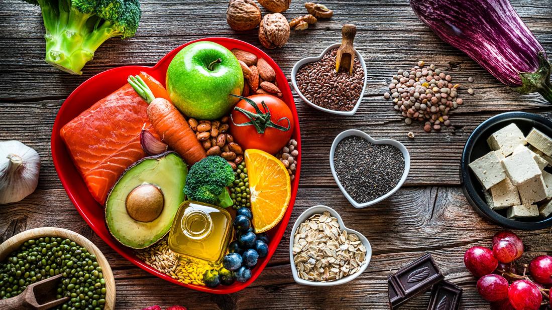 Heart-healthy foods in a heart-shaped dish on wooden table with other heart-shaped filled bowls