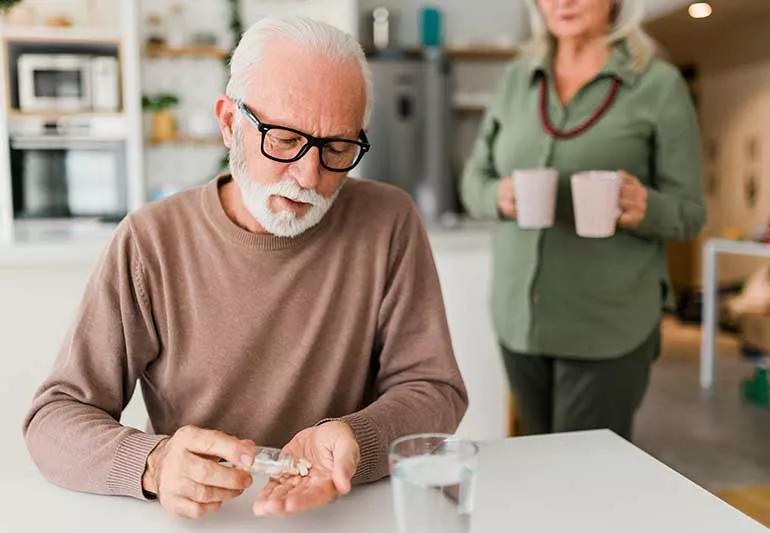 person taking vitamins at breakfast table