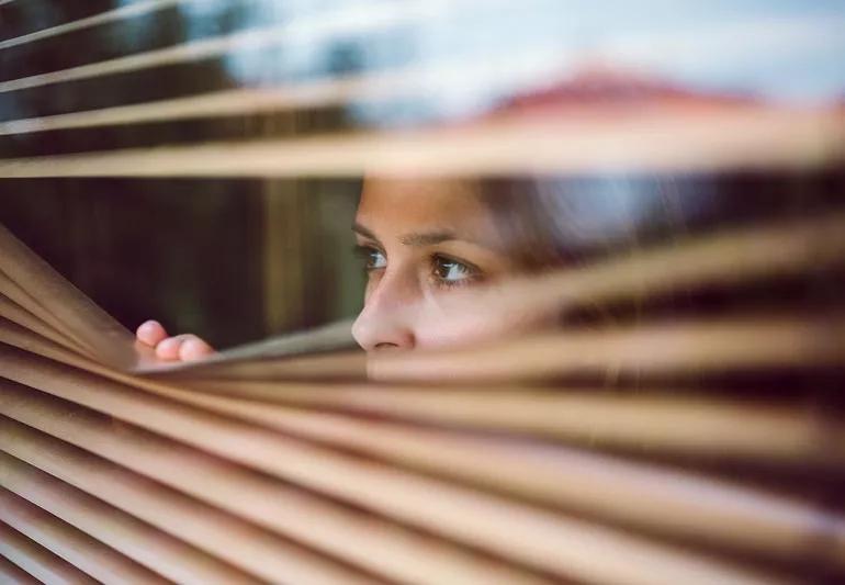 woman frightened looking outside her home