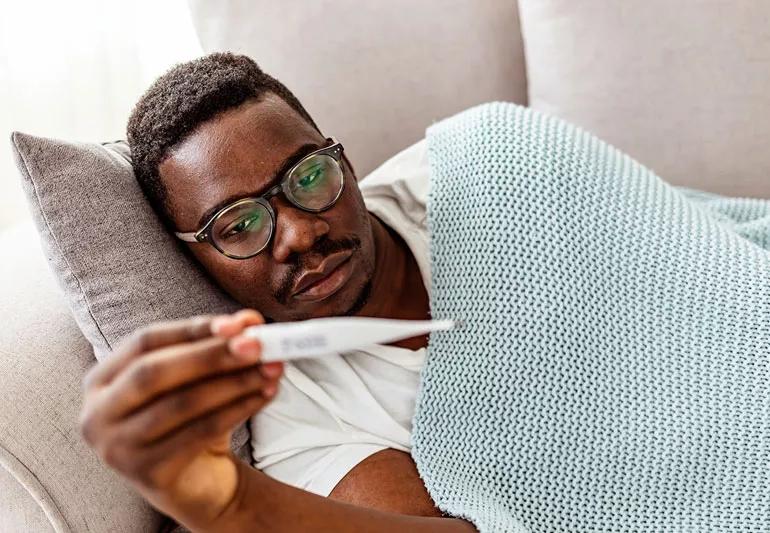 man sick with fever on couch