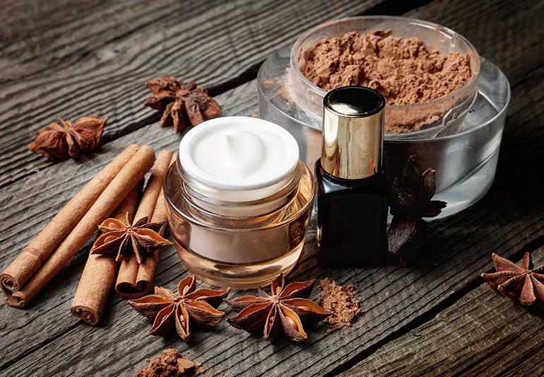 Skin care products on a wood table next to a bowl of brown powder