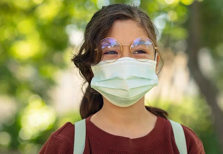 person standing outside wearing surgical mask and glasses