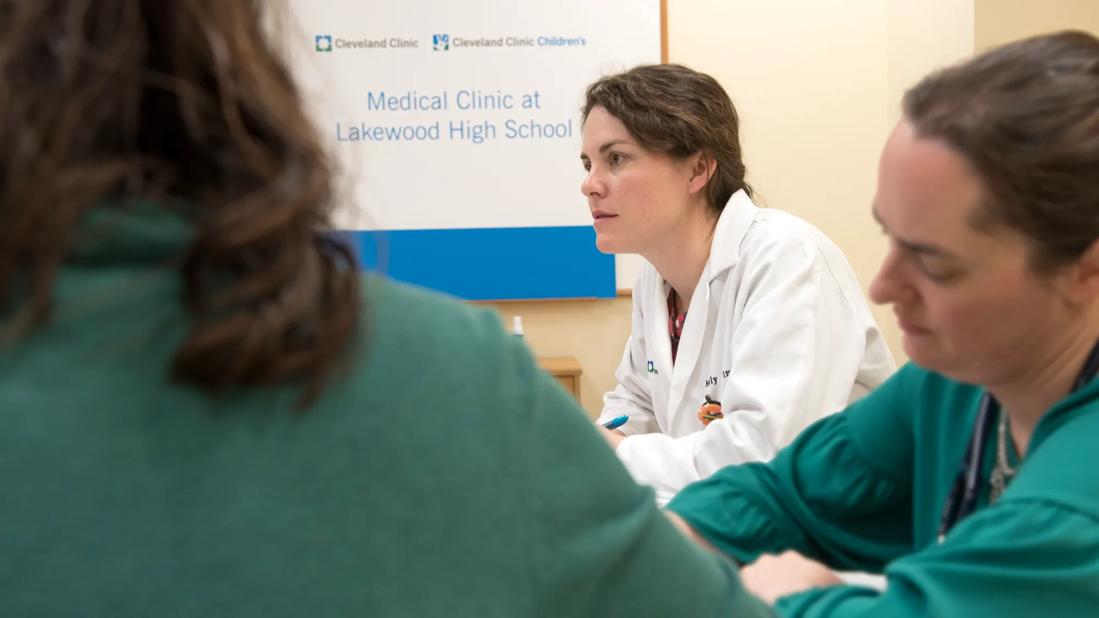 Image of doctor in front of sign with two nurses