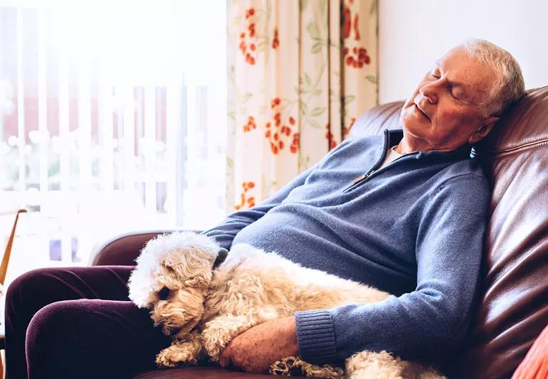 Elderly man takes nap in afternoon with his dog