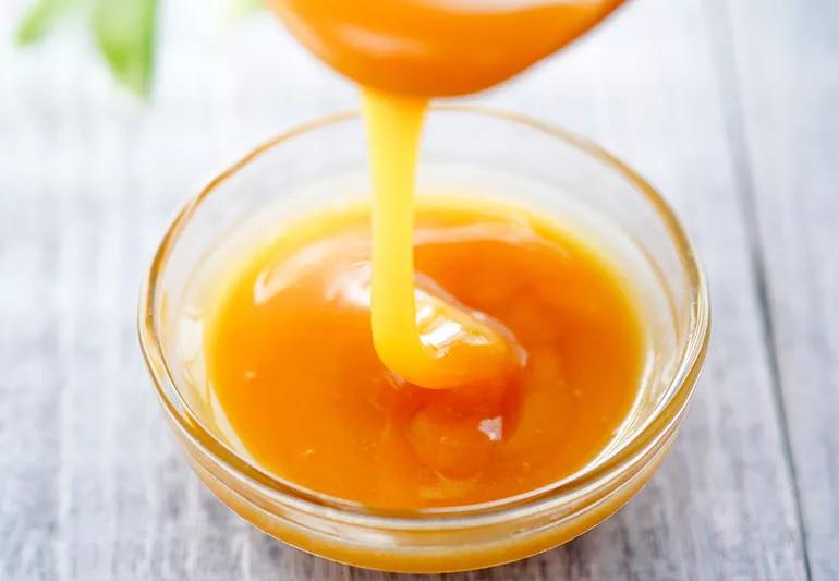 manuka honey being poured into a glass bowl