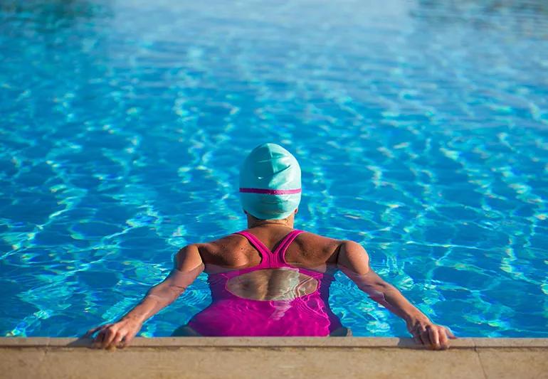Female swimmer in the water at edge of a pool