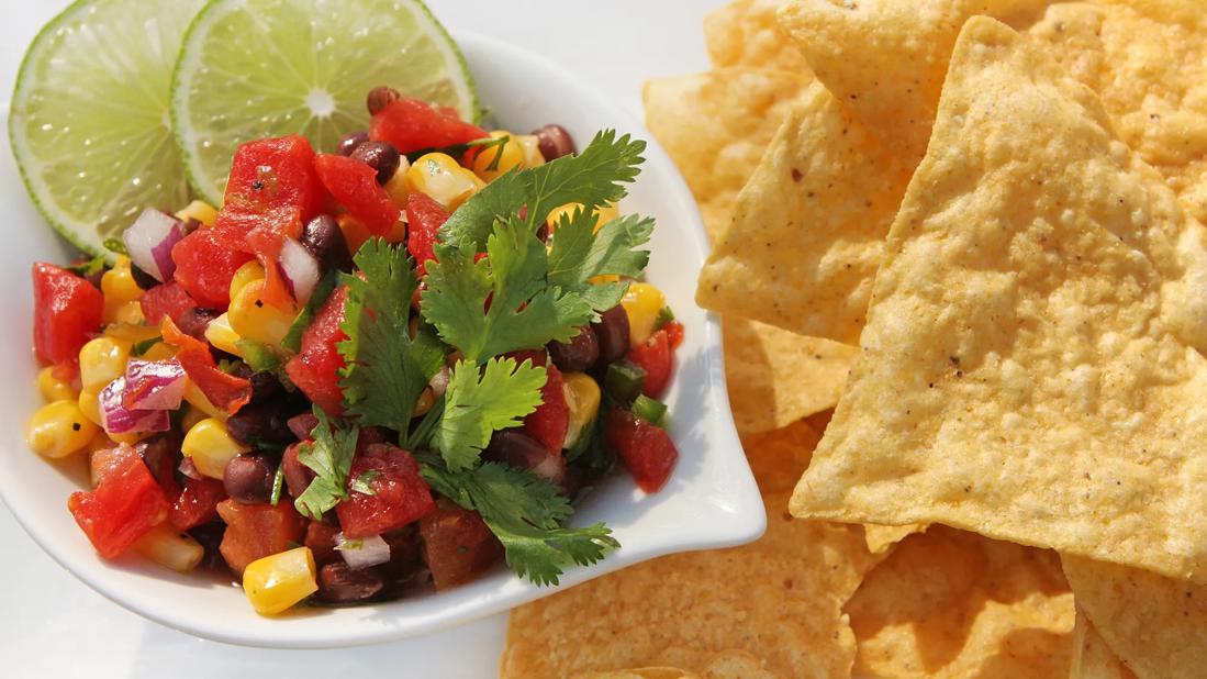 Black bean and corn sasla in dish, with lime garnish and tortilla chips