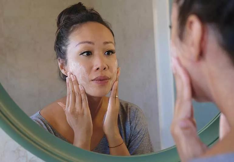 Person using a gentle face cleanser at sink.