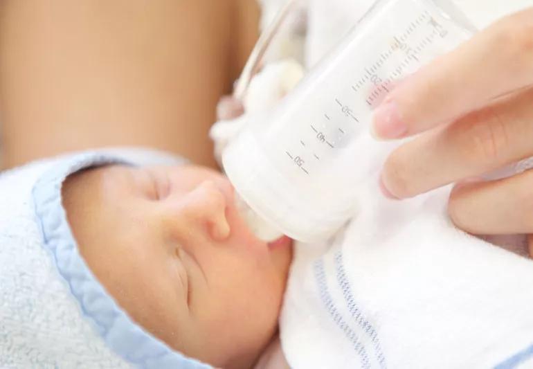 Mother bottle feeding her premature baby