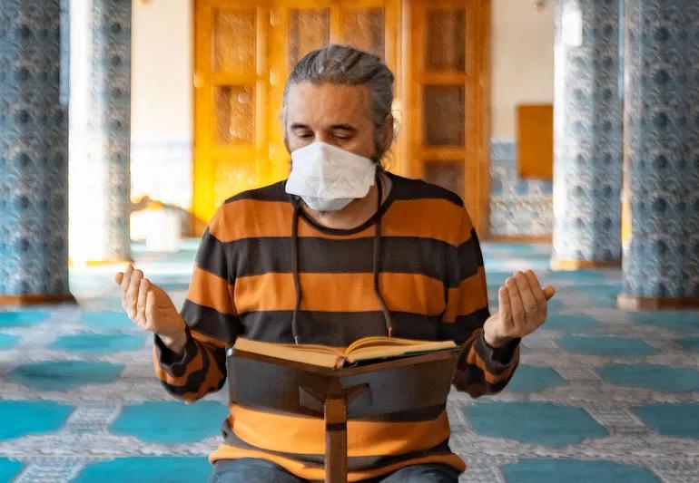 A man reading a book praying in a mosque