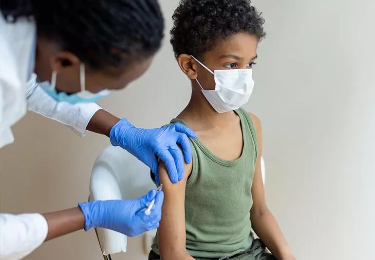 Child receiving Covid-19 booster shot from a healthcare worker.