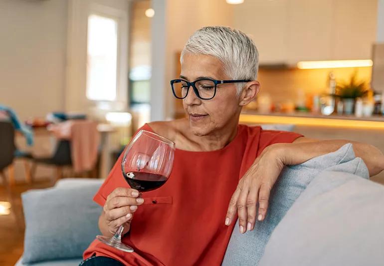 A person sitting on a couch holding a glass of red wine