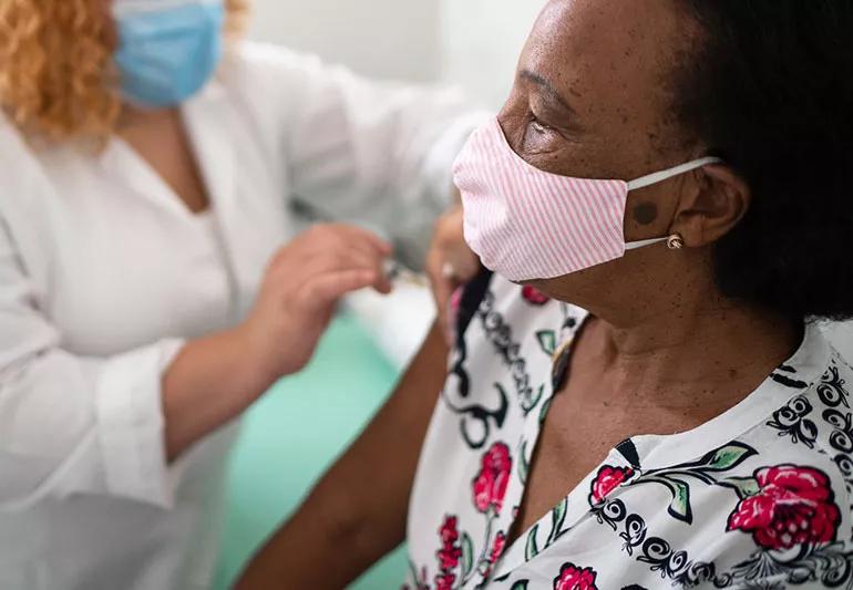 woman getting vaccinated while wearing a mask