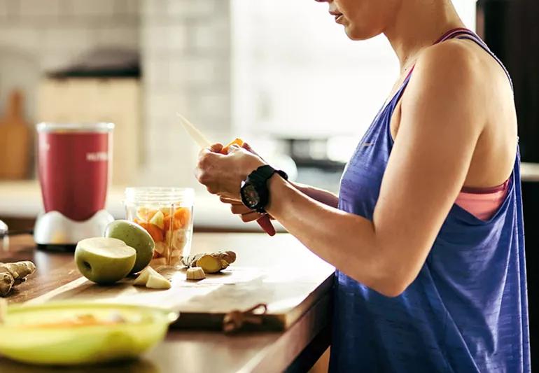 Woman athlete cutting up fruit for a smoothie