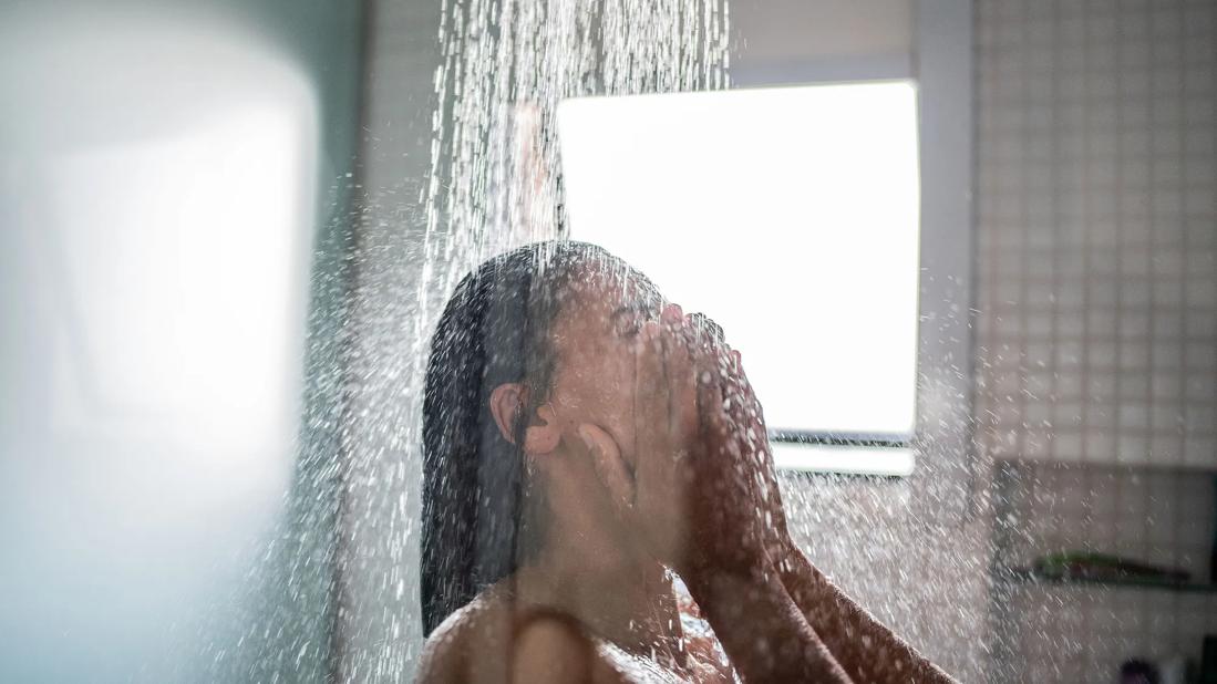 Person in shower, with water running over their face