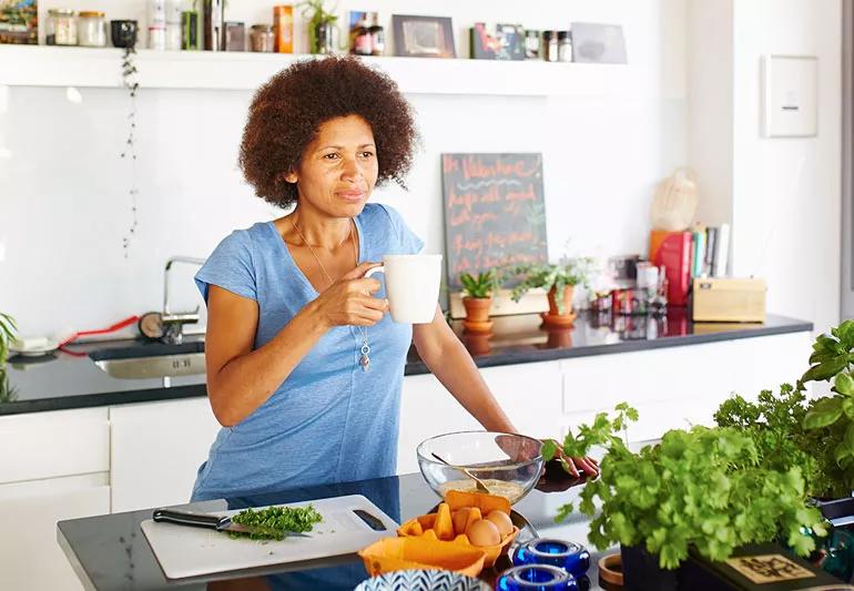 Woman in kitchen drinking coffee