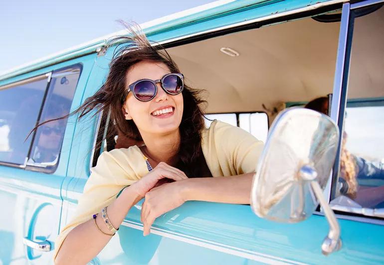 Female hanging out car window wearing sunglasses