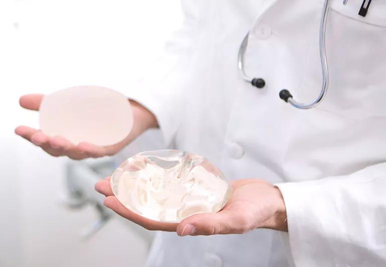 doctor holding different breast implants