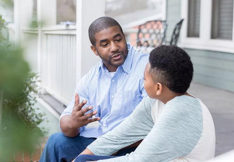 Adult talking to child about vaccines on porch steps